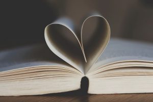Un libro abierto, dos páginas se doblan hacia dentro formando un corazón.